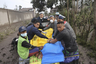Indonesian rescuers and villagers evacuate a victim on a car in an area affected by the eruption of Mount Semeru in Lumajang, East Java.