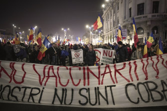 People hold a large banner that reads “No to Vaccination - Our Children are not your guinea pigs” during a protest against vaccinations, the introduction of the green pass and COVID-19 related restrictions in Bucharest.