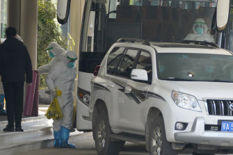 A worker in protective gear carries an exercise dumbbell belonging to the World Health Organization team of experts as they prepare to leave from a quarantine hotel in Wuhan on January 28.