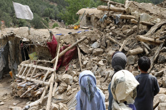Afghan children stand near a house that was destroyed in an earthquake in the Spera District of the southwestern part of Khost Provinc.