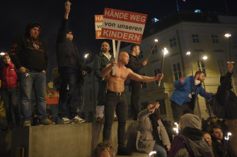 Anti-lockdown protesters hold torches and banners in Vienna, Austria on Saturday. The banner reads “Hands off our Children.” 