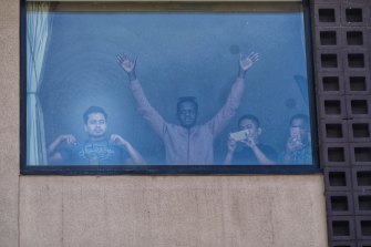 People detained at the Park Hotel in Melbourne wave to protesters in January.