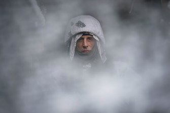 A Ukrainian serviceman, seen through a camouflage mesh, stands at a frontline position in the Luhansk region, eastern Ukraine.