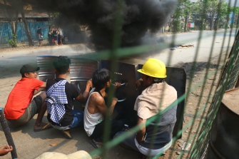 Anti-coup protesters squat with shields in the Hlaing Tharyar township of Yangon on March 14.