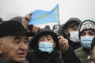 Demonstrators, one of which holds a national flag, gather near a police line during a protest in Almaty, Kazakhstan. Demonstrations started after the government raised the price of fuel at the weekend.