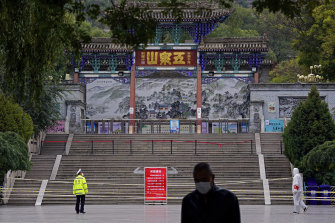 A worker stands at the entrance to Wuquan Mountain which is closed to prevent visitors gathering in Lanzhou city in Gasu province, north-west China, on Monday.