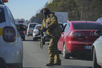 A member of the Ukrainian territorial defence directs cars in a traffic jam ahead of a military checkpoint outside Kyiv.