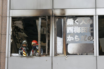 Firefighters stand on a floor at a building where a fire broke out in Osaka on Friday.