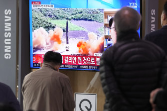 İnsanlar, Mart ayında bir haber programı sırasında Kuzey Kore'nin füze fırlatmasının dosya görüntüsünü gösteren bir TV izliyor.