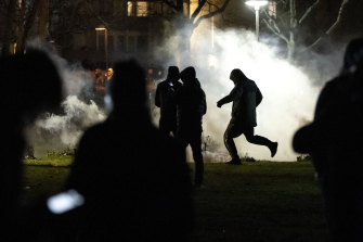 People are silhouetted by smoke after protests broke out at Rosengard in Malmo.