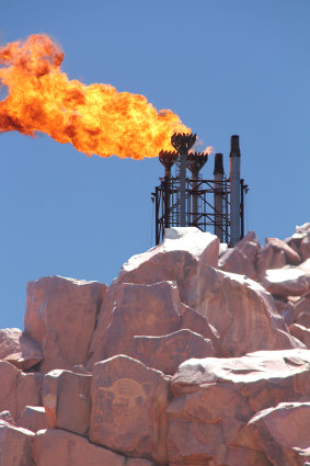 Flare tower of Woodside’s Pluto LNG plant in WA with an Indigenous rock engraving of an echidna in the foreground.