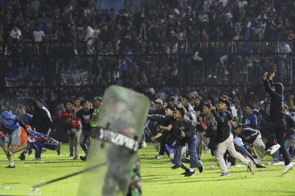Soccer fans enter the pitch during a clash between supporters at Kanjuruhan Stadium in Malang, East Java on Saturday.