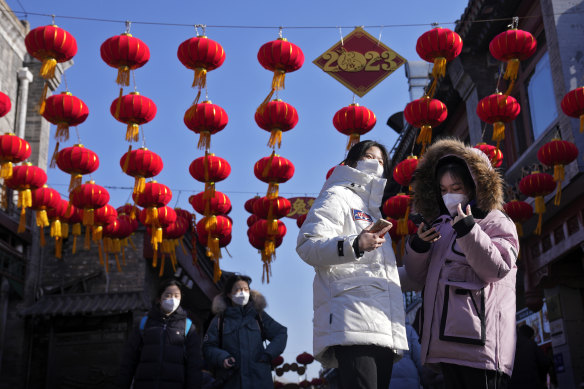 Visitors tour past red lanterns hanging on a shopping alley near the Houhai Lake for celebrating the Lunar New Year in Beijing on Monday.