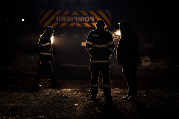 Firefighters stand next to a Turkey-bound train loaded with emergency aid for building shelters, at a railway station in Romania on Saturday.