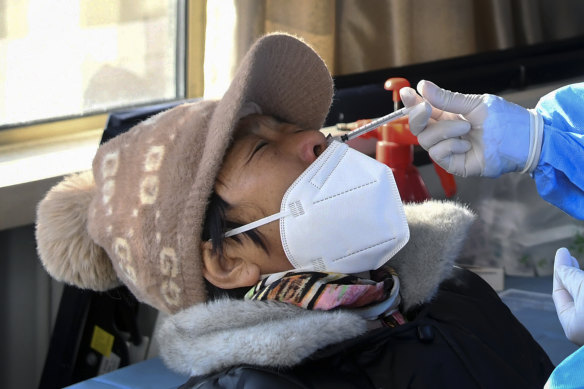 A woman receives a second booster dose of COVID-19 vaccine through the nose, at a temporary vaccination site in Beijing, in mid-December.