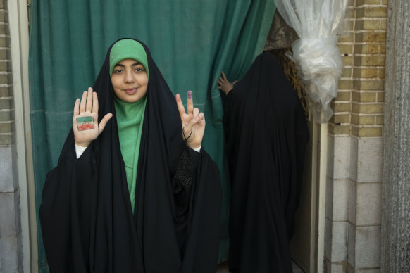 An Iranian woman shows her ink-stained finger after casting her ballot for 12th term of the parliamentary elections and the 6th term of the Assembly of Leadership Experts at a polling station in Tehran.