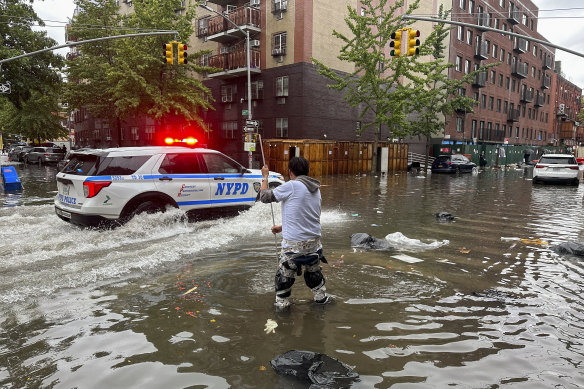A man works to clear a drain in flood waters in Brooklyn.