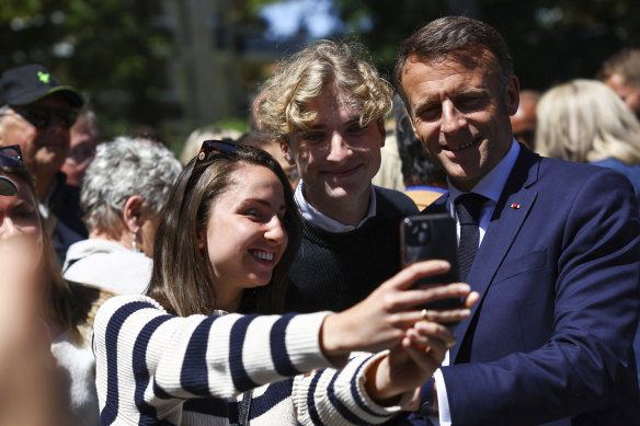 French President Emmanuel Macron poses for pictures outside a polling station during the European election, in northern France.