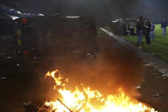 Plain-clothed officers stand near the wreckage of police vehicles damaged in the clashes.