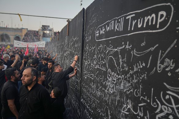 Mourners write messages on a wall, including one in English that reads "We will kill Trump," during the funeral ceremonies for slain Iranian Supreme Leader Ayatollah Ali Khamenei and members of his family.