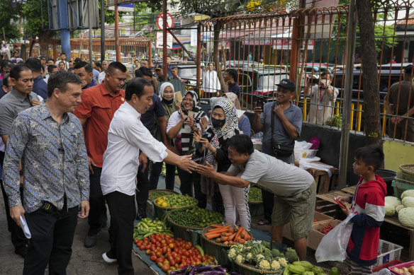 Chris Barrett, left, found himself shepherded in beside Indonesian President Joko Widodo during his tour of Palmerah market in Jakarta.