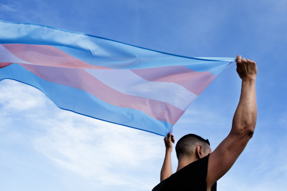 A man holds up a transgender flag.