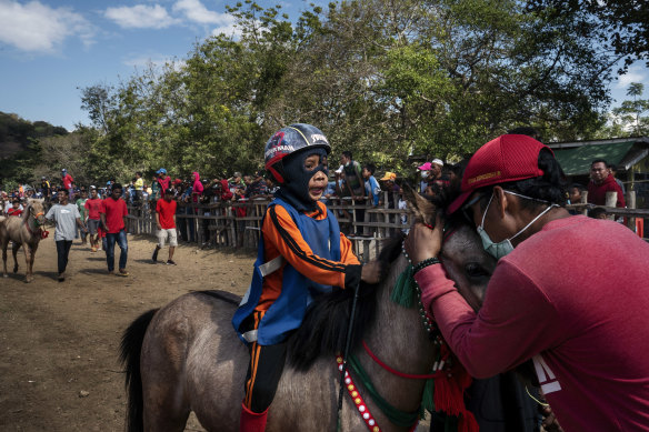 An owner embraces his horse ridden by a child jockey.