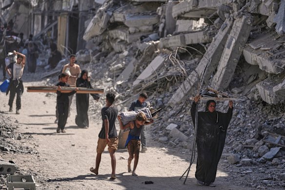 Palestinos deslocados passam por edifícios destruídos enquanto retornam para suas casas em Khan Younis na sexta-feira.