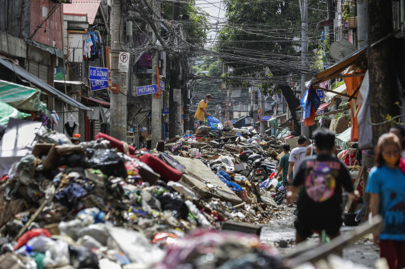 Residents climb over piles of debris washed in floodwaters from typhoon Vamco in Marikina, Philippines.