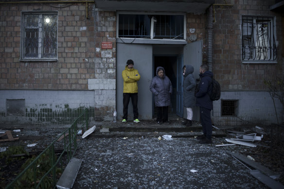 People stand amid glass from broken windows of their apartment building following a Russian drone attack in Kyiv on Saturday.