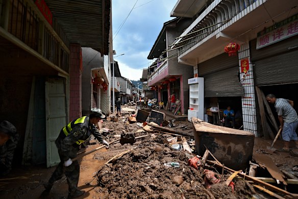 People clean up silt and garbage at a village following a flooding in Xiangxi on Sunday.