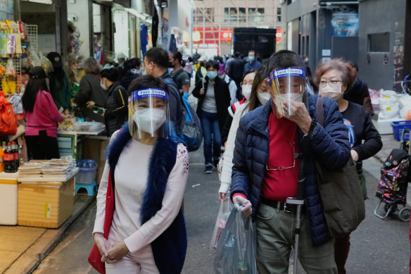 People wearing protective masks walk through an outdoor market in Hong Kong.