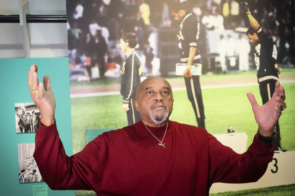 Tommie Smith gestures in front of the famous photograph of him, Norman and Carlos at the 1968 Olympics, at the Immigration Museum, in Paris.