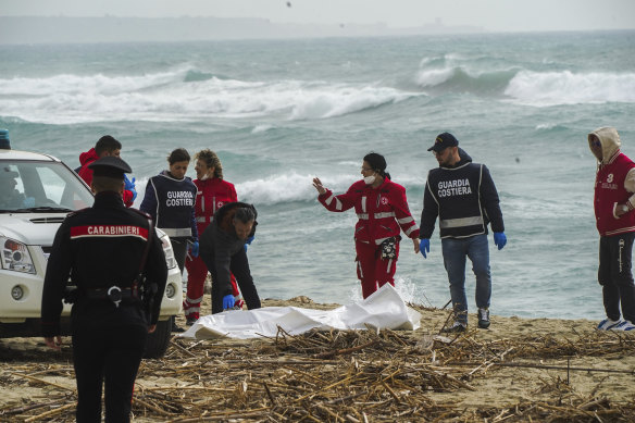 Italian Red Cross volunteers and coast guards recover a body after a boat broke apart in rough seas.