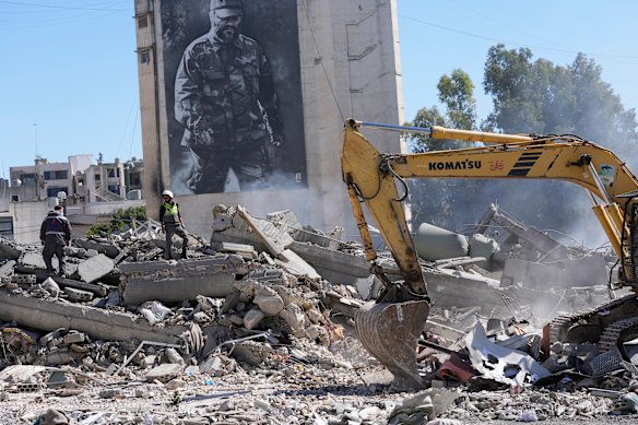 A giant poster shows the late Hezbollah military commander Imad Mughniyeh, while workers check a destroyed building that was hit by an Israeli airstrike in Nabatiyeh, south Lebanon, in early March.