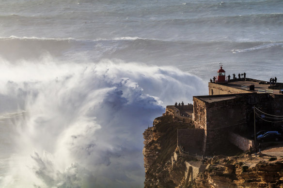 Giant waves crash into the Nazare Lighthouse in Praia do Norte, Portugal.