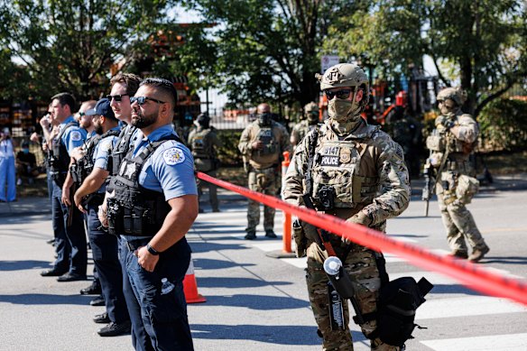 Os policiais do Departamento de Polícia de Chicago estão em frente a oficiais federais no bairro de Brighton Park, em Chicago, no sábado.
