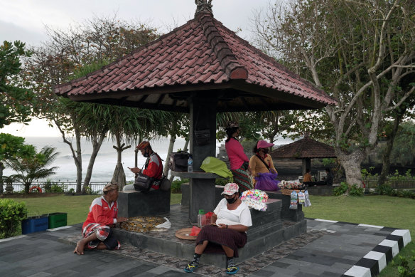 Street vendors sit together in the absence of tourists in Tanah Lot, Bali, last month. 