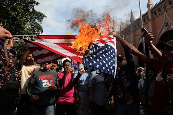 Supporters of Nicolas Maduro burn a United States flag during a gathering near Miraflores palace in Caracas.