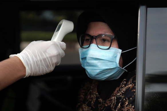 A motorist has her temperature checked at a checkpoint in Jakarta, Indonesia, on Friday. 