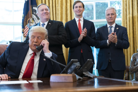 Donald Trump talks on the phone to the leaders of Sudan and Israel, as Secretary of State Mike Pompeo, left, White House senior adviser Jared Kushner and National Security Adviser Robert O'Brien applaud.