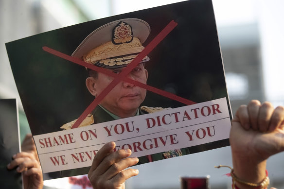 A Burmese protester living in Thailand holds a picture of Myanmar military chief Min Aung Hlaing.