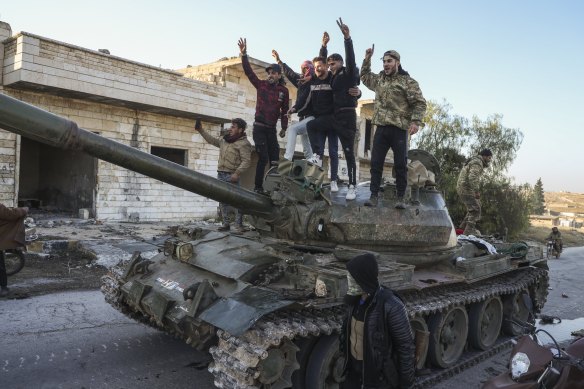 Syrian opposition supporters stand on a captured Syrian army tank in the town of Maarat al-Numan on Saturday.