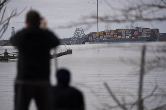 Locals take in the extraordinary sight of the shattered Francis Scott Key Bridge.