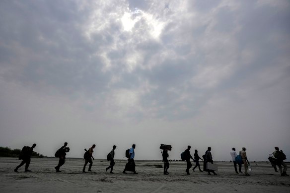 Polling officials carry Electronic Voting Machines (EVMs) across a dried riverbed of Brahmaputra on the eve of the national election at Baghmora Chapori (small island) of Majuli, about 350km east of the state capital Guwahati, India.