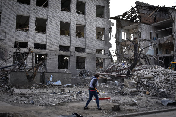 A resident clears debris near a building damaged in the Russian air raid in Orikhiv, Ukraine.