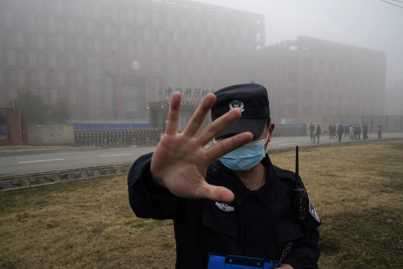 A security person moves journalists away from the Wuhan Institute of Virology in February 2021.