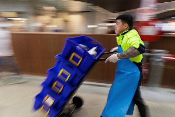 Um trabalhador transporta frutos do mar pela principal área de varejo do mercado de peixes no domingo.