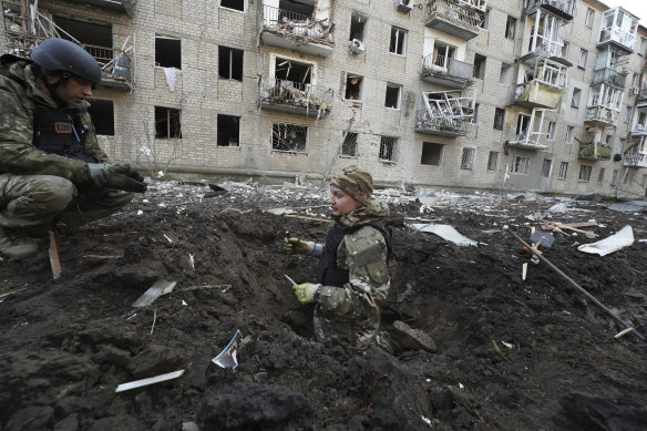 Police officers inspect a crater in front of a damaged residential building hit by a Russian strike in Kharkiv, Ukraine, on Wednesday. 