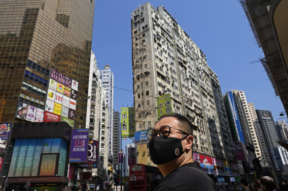 Hong Kong'da yüz maskesi takan bir adam şehir merkezindeki bir caddede yürüyor.
